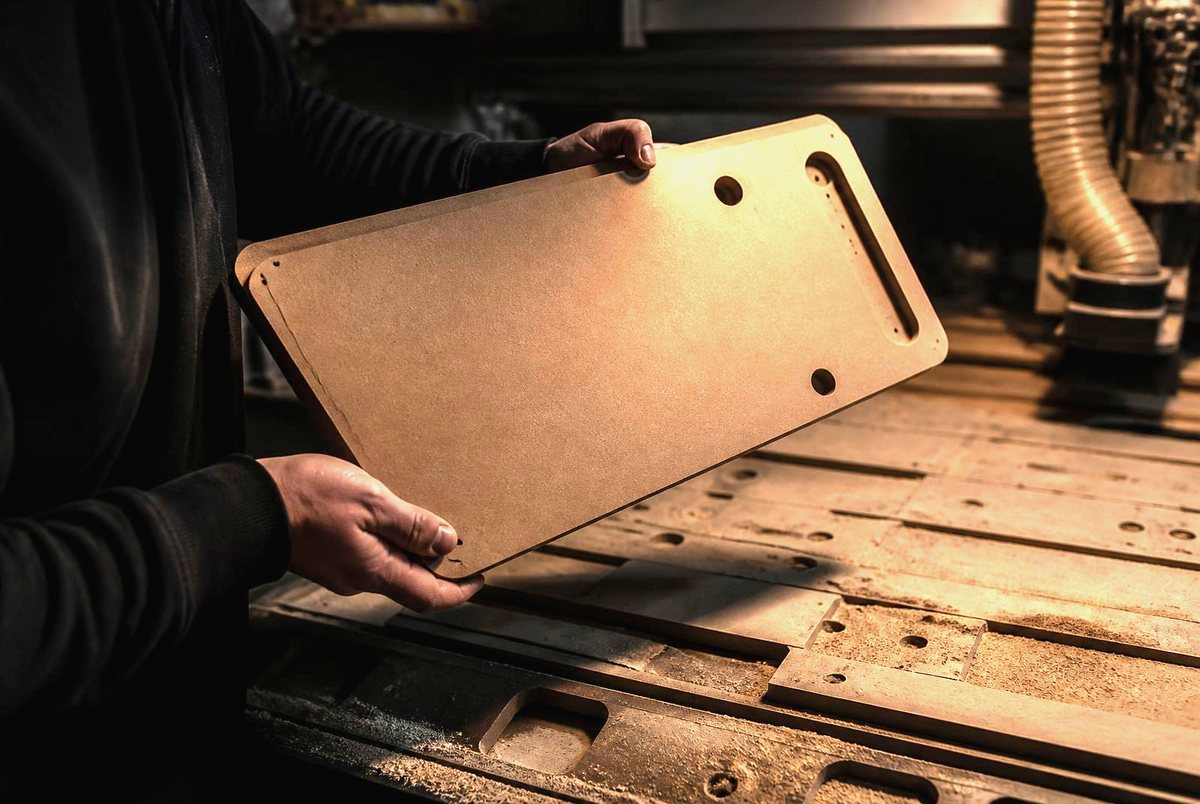 Drilled cabinet part coming off the CNC bed